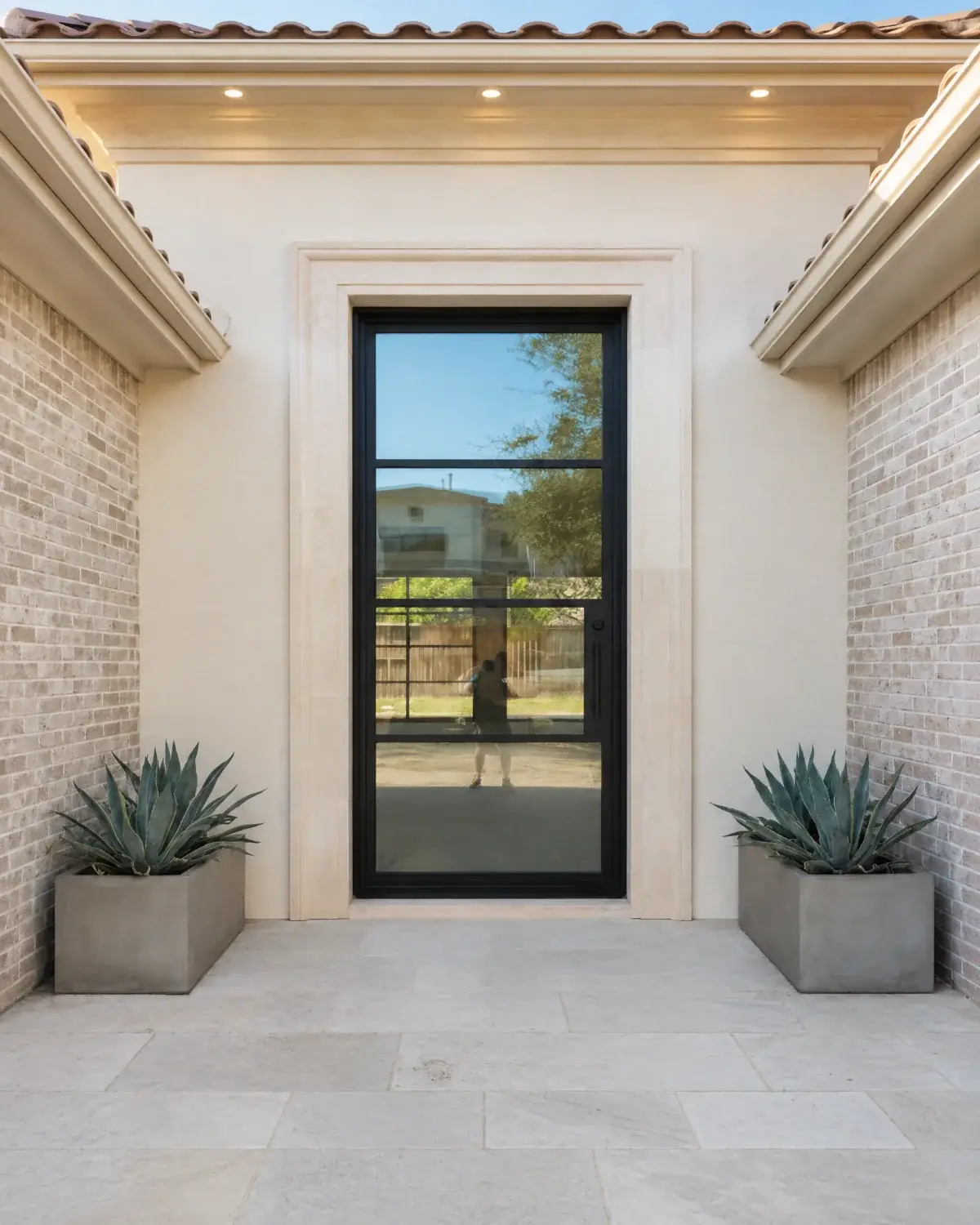 Single black iron entry door with clear glass in a limestone surround
